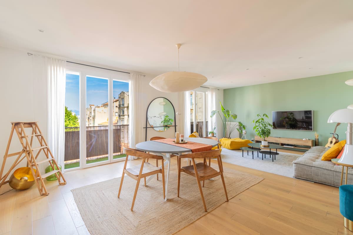 Salon lumineux avec mur vert sauge et balcon